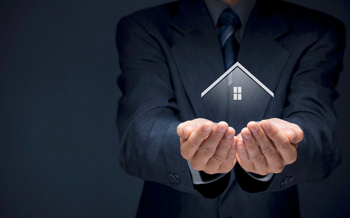 Man in a suit holding a digital house icon in his hands against a dark background