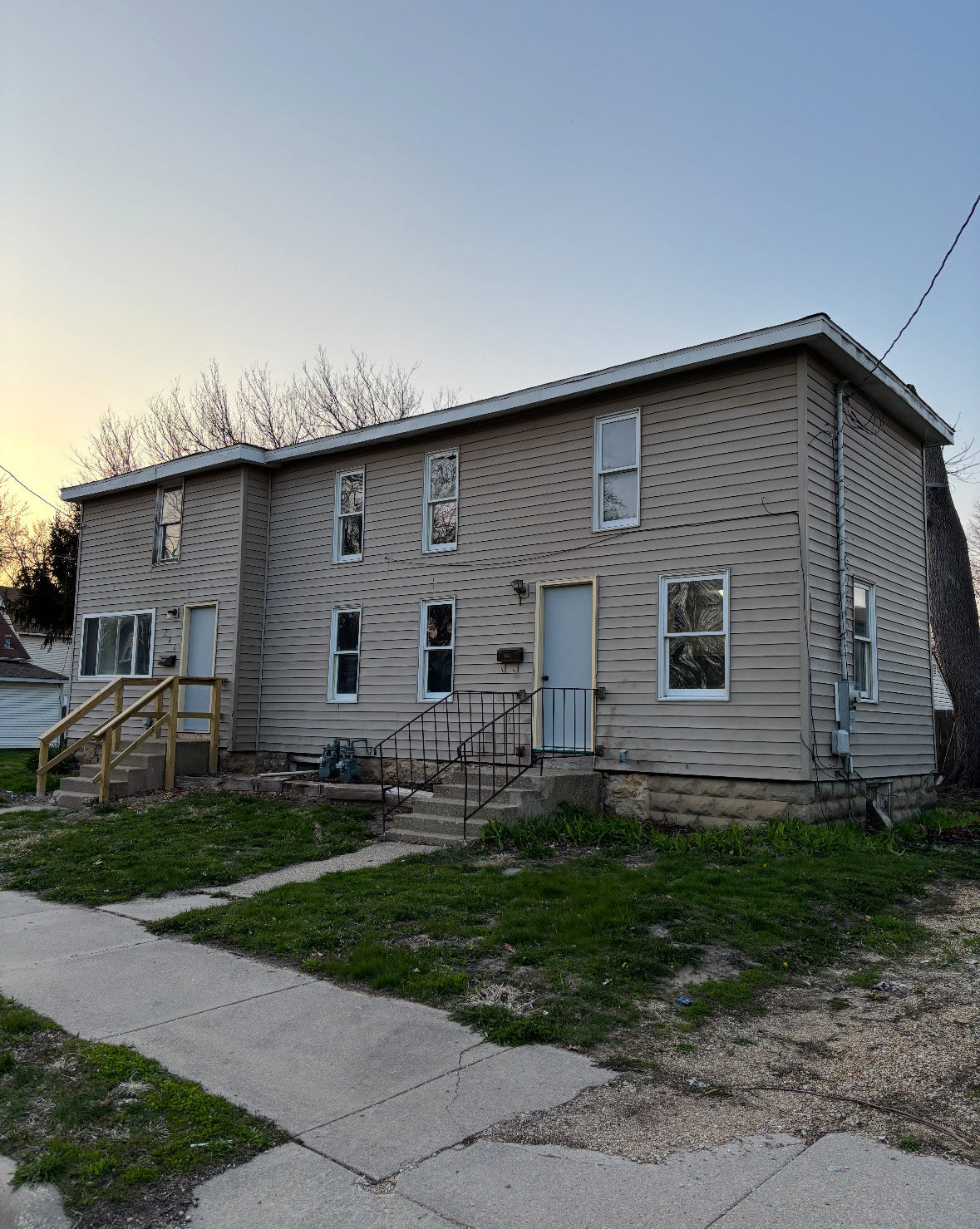 Two-story house with beige siding and a front porch on a clear day.